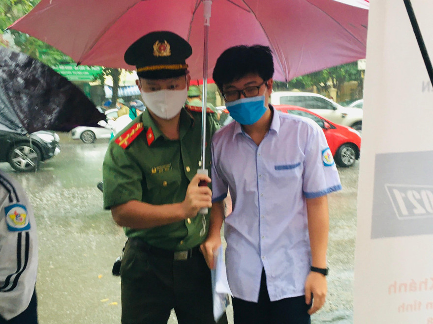 Hình ảnh đẹp chiến sĩ công an dầm mưa che chắn cho sĩ tử 