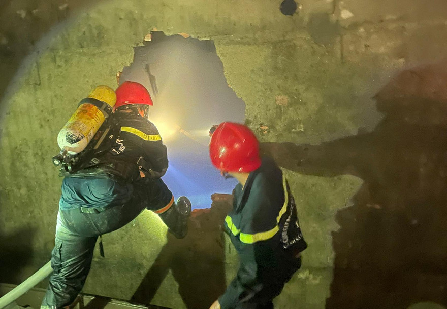 Lính cứu hỏa đục tường vào nhà tìm nạn nhân.