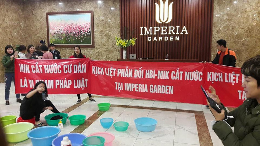 Bị cắt nước đầu năm, cư dân chung cư 203 Nguyễn Huy Tưởng mang băng rôn và xô chậu xuống sảnh phản đối.