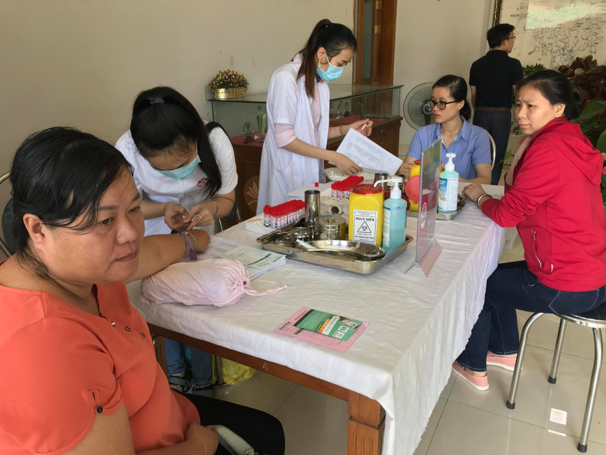 Nhân viên y tế lấy mẫu máu tầm soát ung thư cho người lao động.