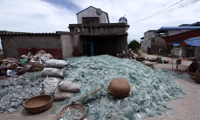 Mảnh kính vỡ được gia đình anh Phạm Ngọc Hân, chủ một lò thổi thủy tinh ở làng Xối Trì chất thành đống lớn giữa sân nhà