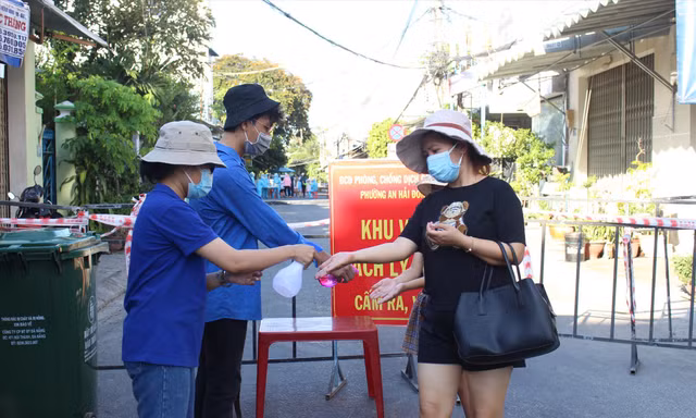 Tình nguyện viên ở chốt phong tỏa “mềm” đường An Dương Vương (quận Ngũ Hành Sơn) hỗ trợ người dân ra vào khu cách ly. - Ảnh: Giang Thanh