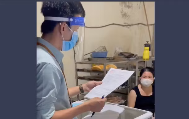 Cán bộ phường Vĩnh Hoà đọc biên bản xử lý chủ cơ sở bánh mì ở đường Điện Biên Phủ, TP. Nha Trang. Ảnh chụp lại clip.