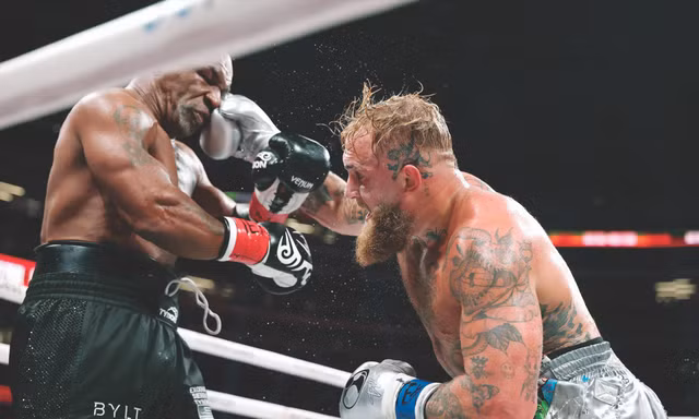 Mike Tyson (trái) chịu đựng cú đấm của đối thủ. Ảnh: Getty Images 