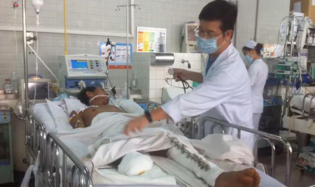 Bác sĩ Huy đang thăm khám cho anh Tám tại khoa hồi sức cấp cứu Bệnh viện Chợ Rẫy. Ảnh: Quốc Ngọc.