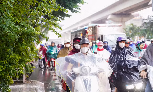 Người dân di chuyển khó khăn trong cơn mưa kéo dài đầu giờ sáng tại Hà Nội.
