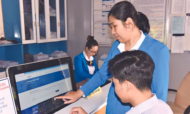 Nhân viên Công ty Điện lực Bình Thuận hướng dẫn khách hàng thao tác thanh toán tiền điện trực tuyến Ảnh: Văn Hơn 