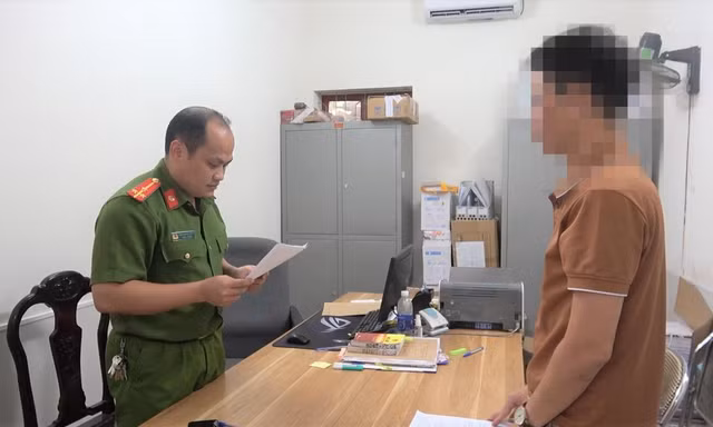 Ông L.V.Q (bìa phải) nghe quyết định khởi tố bị can, khởi tố vụ án trốn thuế -Ảnh: TL