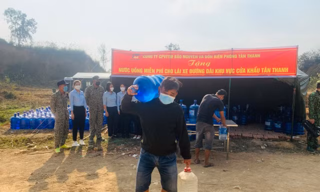 Lái xe chở nông sản vui mừng được phát bình nước sạch miễn phí -Ảnh: Duy Chiến 