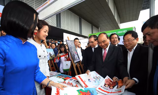 Tổng Biên tập báo Tiền Phong Lê Xuân Sơn giới thiệu các ấn phẩm của báo với Thủ tướng Nguyễn Xuân Phúc tại gian hàng.