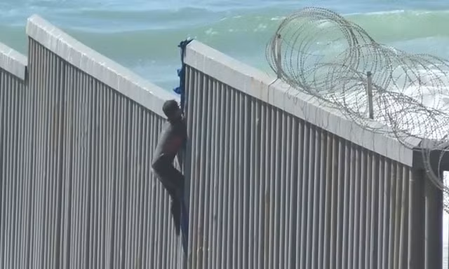 Người di cư ở Mexico trèo tường biên giới để vào Mỹ