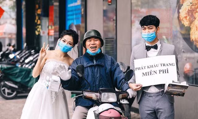 Chú rể Nghiêm Đình Đăng và cô dâu Phạm Ngọc Vy tặng khẩu trang miễn phí cho người dân Hà Nội. ảnh: Windy Wedding.