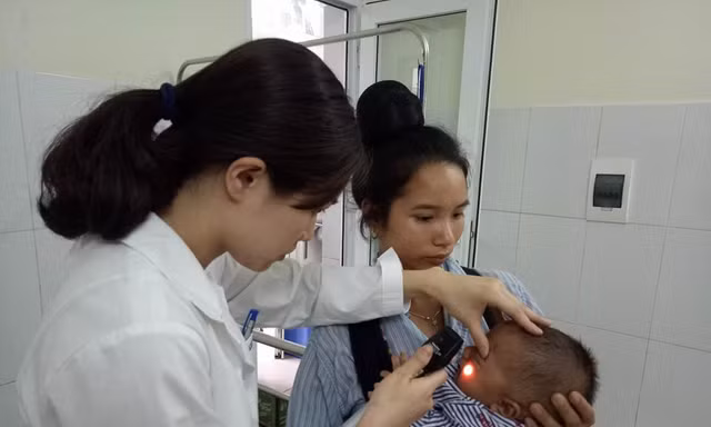 Bác sĩ Vũ Quế Anh đang xem xét tình trạng hoại tử của bé Kiên trước khi phẫu thuật cắt bỏ hoàn toàn. Ảnh: Đinh Tuấn.