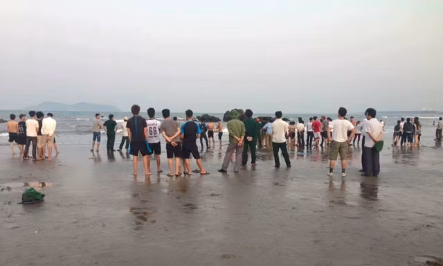 Người dân tập trung nơi bãi biển xảy ra vụ hai học sinh bị sóng cuốn mất tích khi đi chụp ảnh kỷ yếu.
