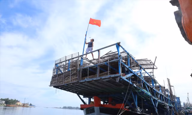 Ngư dân thay mới cờ Tổ quốc sẵn sàng vươn khơi. Ảnh: Hoài Văn