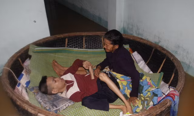Hai mẹ con bà Đắt trong chiếc thuyền thúng nổi trôi theo nước lũ. Ảnh: Thanh Trần. 