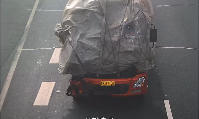 Thay vì đi thay kính, tài xế xe tải đã dùng bạt bịt kín đầu xe, khoét một lỗ nhỏ để nhìn đường.