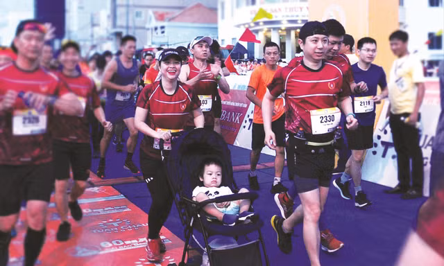 Gia đình chị Nguyễn Quỳnh Chi - Trần Phan Linh (38 tuổi) cùng con trai trên xe nôi xuất phát Ảnh: Xuân Tùng