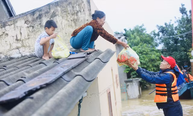 Bà Biên Thị An nhoài người nhận hàng cứu trợ 