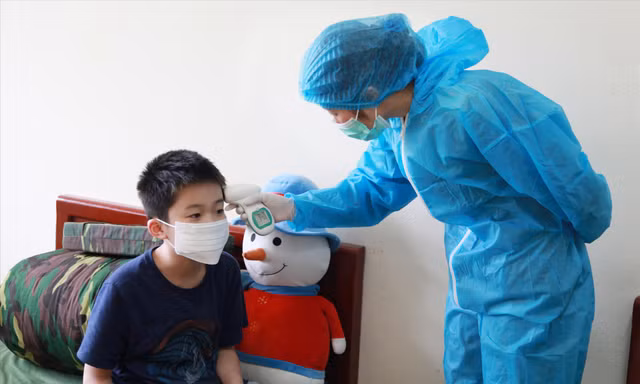 Quân y Bùi Thị Thắm kiểm tra thân nhiệt cho một cháu nhỏ trong khu cách ly ẢNH: PV 