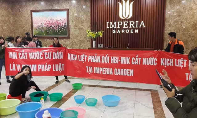 Bị cắt nước đầu năm, cư dân chung cư 203 Nguyễn Huy Tưởng mang băng rôn và xô chậu xuống sảnh phản đối.