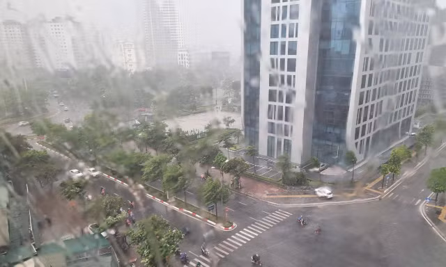 Mưa to gió lớn khiến người đi xe máy không thể di chuyển ở đoạn đường gần khu Đại sứ quán Mỹ thuê