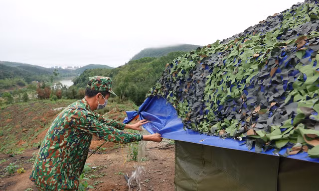 Trung tá quân nhân chuyên nghiệp Bùi Văn Bách tháo nước đọng trên mái che lán dã chiến Ảnh: Nguyễn Minh
