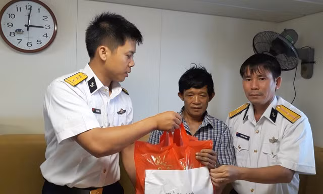 Thuyền trưởng Lê Văn Chung (bên trái) động viên, trao quà cho ngư dân tàu cá bị nạn, năm 2018