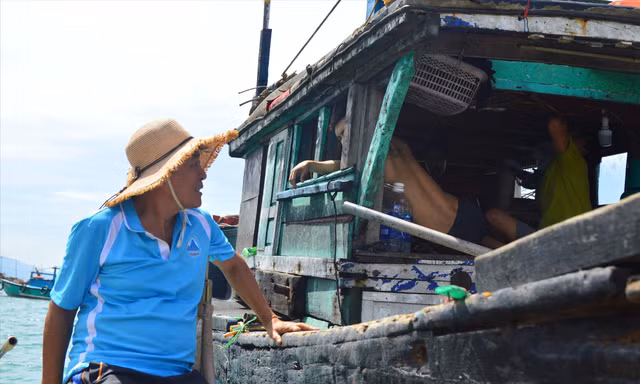 Lão ngư Nguyễn Quang tranh thủ vừa thả lưới, vừa tuyên truyền cho các ngư dân trên các tàu đánh bắt gần bờ. Ảnh: Giang Thanh 