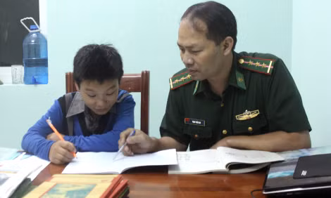 Đại uý Phạm Trần Duy - nhân viên Đội vận động quần chúng Đồn Biên phòng Xín Mần, Hà Giang kèm cháu Vàng Củi Vu. Ảnh: BTC