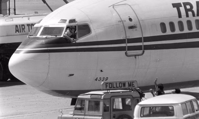 Một tên không tặc cầm súng lục bên cửa sổ máy bay. Ảnh: Getty.