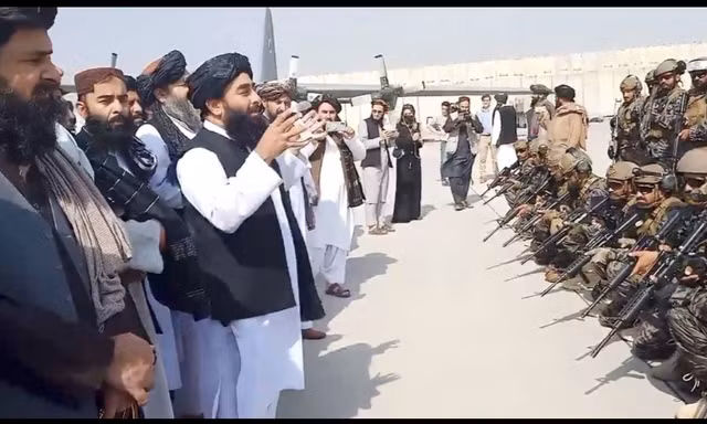 Phát ngôn viên Taliban Zabihullah phát biểu trước một nhóm tay súng tại sân bay Kabul ngày 31/8 Ảnh: Al Jazeera 