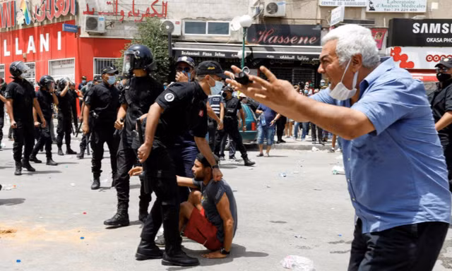 Một người đàn ông phản ứng khi cảnh sát bắt một người biểu tình ở Tunis ngày 25/7. (Ảnh: Reuters)
