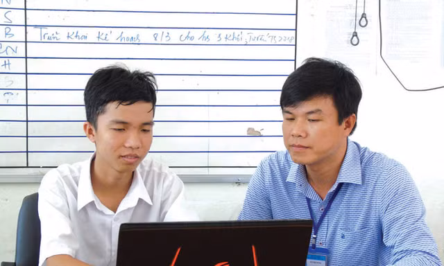 Em Trần Lê Duy (bên trái) và thầy Võ Việt Dũng kiểm tra một số phần mềm đã lập trình. Ảnh: Kim Hà.