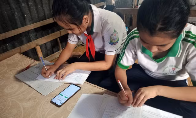 Hai học sinh học trực tuyến chung bằng một chiếc điện thoại