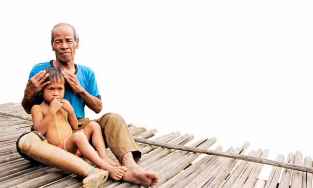 Ông Mơ đang ôm cháu Hồ Dừa (4 tuổi, mồ côi cha mẹ) vào lòng nâng niu, vỗ về. Ảnh: H.T.