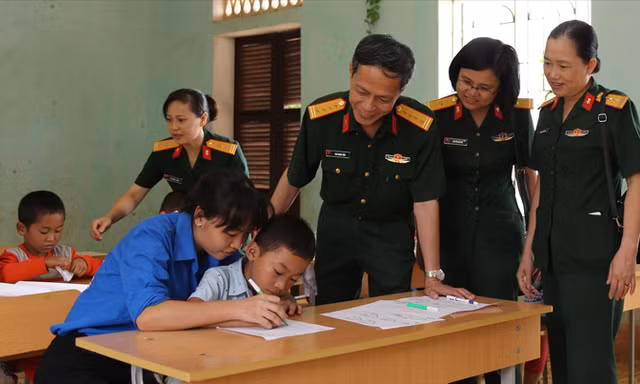 Đại tá Cao Minh Tiến và đoàn công tác kiểm tra thực tế việc bổ trợ kiến thức cho học sinh cấp 1 của đội tình nguyện tại trường Tiểu học và THCS xã Bắc Sơn. Ảnh: Nguyễn Minh.