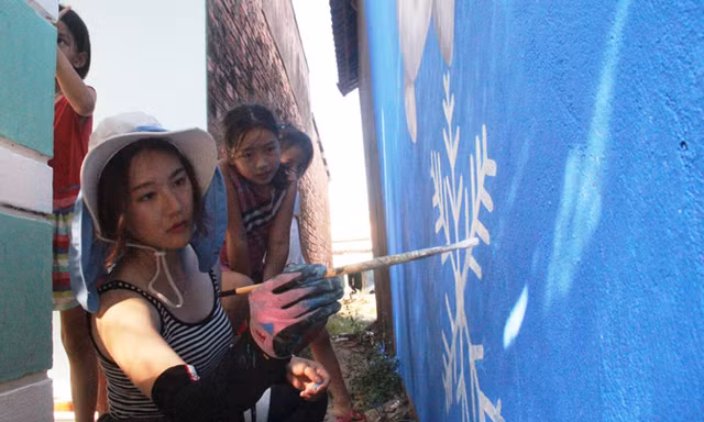 Họa sĩ Oh Ye Seul đang hoàn tác bức tranh người tuyết trên tường nhà dân Tam Thanh. Ảnh: H.Văn.