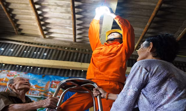 Vợ chồng ông Phan Thanh Quang (ấp Mũi, xã Đất Mũi, Ngọc Hiển, Cà Mau) vui mừng được công nhân ngành điện thay thế đường dây, bóng đèn mới.