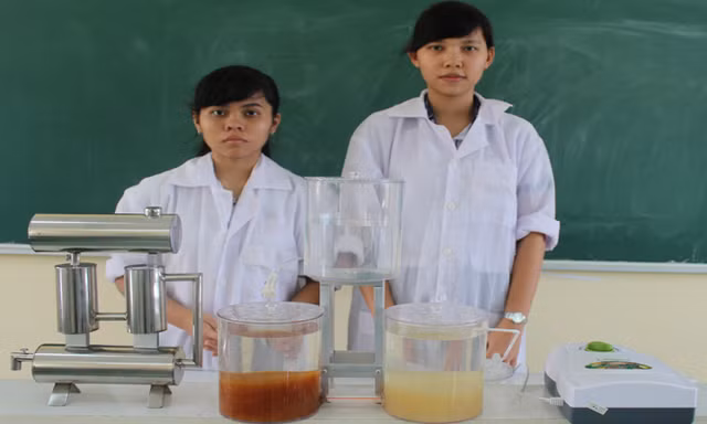 Thảo Quỳnh (bìa phải) và Hoàng Yến cạnh mô hình “Hệ thống xử lý nước mưa khép kín”. Ảnh: Xuân Lương.