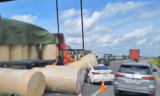 Nhiều cuộn giấy trên xe đầu kéo rơi xuống đường, đè trúng ô tô con
