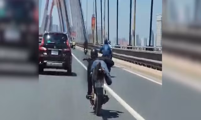Thanh niên nằm trên yên điều khiển xe máy, phóng vun vút qua cầu Nhật Tân