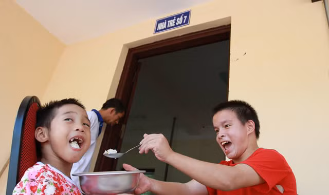 Hai em nhỏ tự đút cơm cho nhau ăn rất ngon lành. Ảnh: Minh Đức