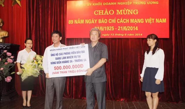 Ông Trần Bá Huấn (áo trắng) trao tặng món quà của VDB. Ông Hà Minh Huệ thay mặt cho các PV tiếp nhận. Ảnh: Trần Việt Hải 