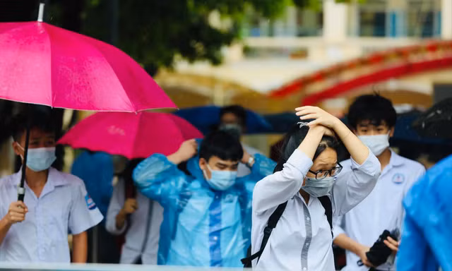 Thí sinh đội mưa đến điểm thi ở Hà Nội ngày 13/6. Ảnh: Như Ý 