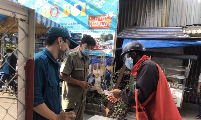 Người dân khu phong tỏa khi có chuyện khẩn cấp sẽ được xem xét cấp giấy ra khỏi chốt chặn Ảnh: U.P 