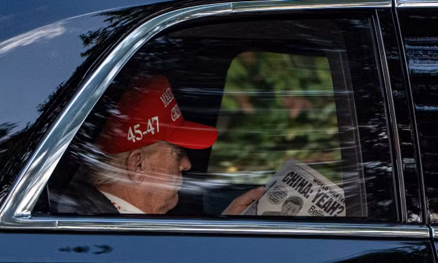 Tổng thống Donald Trump đọc báo khi trên đường đến Câu lạc bộ Golf quốc gia Trump ngày 5/4. (Ảnh: AP)
