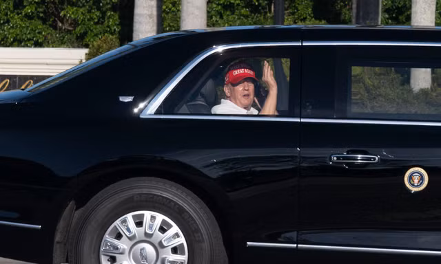 Tổng thống Mỹ Donald Trump vẫy tay khi đang ngồi trên chiếc limousine trở về khu biệt thự và sân golf của ông ở West Palm Beach ngày 8/3. (Ảnh: AP)