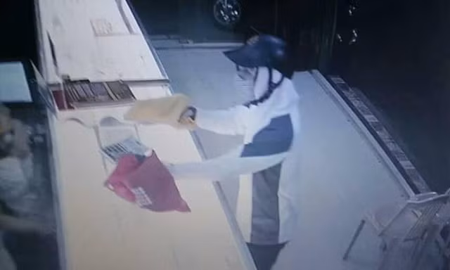 Tên cướp giơ vật gống khẩu súng được giấu trong chiếc túi màu vàng. Ảnh cắt từ video.