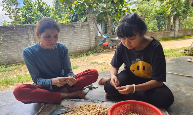 Chị H’Grôn Bkrông (trái) cùng con gái bóc vỏ hạt điềuẢnh: Huỳnh Thủy 